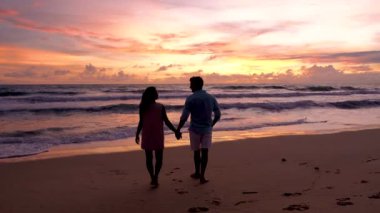 A couple of men and women walking on the beach during sunset in Phuket Thailand, a couple on vacation in Thailand during the summer holiday