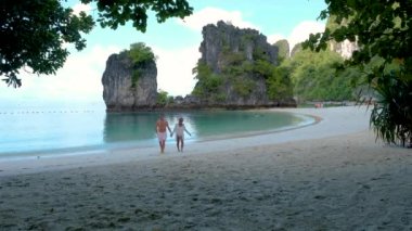 couple of caucasian men and Asian women on a tropical white beach in Thailand, Koh Hong Island Krabi during summer vacation in Thailand