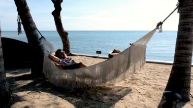 a couple of men and women on a tropical white beach in a hammock during sunset in Thailand, during summer vacation in Thailand Hua Hin