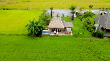 Couple on vacation at a homestay farm in Thailand with green rice fields, men and women at a farm Bed and Breakfast eco stay in Thailand