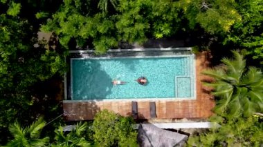 drone view from above a couple in a swimming pool in the rainforest jungle. 