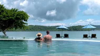 a couple of men and women relaxing in a swimming pool during a vacation in Thailand. men and women on vacation in Thailand during rainy season