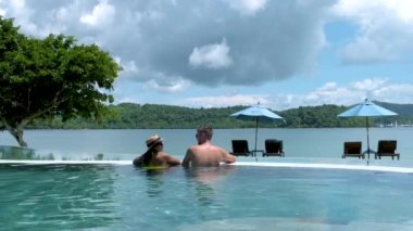 a couple of men and women relaxing in a swimming pool during a vacation in Thailand. men and women on vacation in Thailand during rainy season