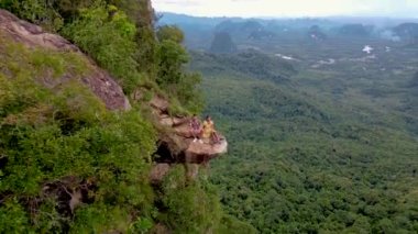 Ejderha Tepesi dağı Krabi Tayland, genç bir gezgin uçurumun üzerindeki kayanın üzerinde oturuyor, güzel bir manzarası var. Tayland, Krabi 'deki Khao Ngon Nak Doğa Yolu' nda Ejder Tepesi veya Khuan Sai..