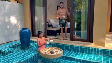 couple of men and woman having breakfast in a pool on a luxury vacation at a pool villa in the rainforest jungle mountains