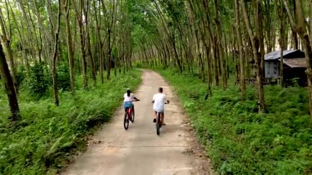 泰国农村的一对夫妇骑自行车在橡胶树间骑车 — 图库视频影像