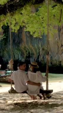 a couple of men and women on a tropical white beach at a swing in Thailand, Koh Lao Lading Krabi during summer vacation in Thailand during a trip to Koh Hong Islands