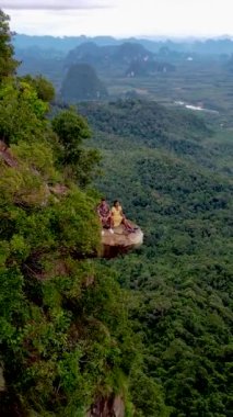 Ejderha Tepesi dağı Krabi Tayland, genç bir gezgin uçurumun üzerindeki kayanın üzerinde oturuyor, güzel bir manzarası var. Tayland, Krabi 'deki Khao Ngon Nak Doğa Yolu' nda Ejder Tepesi veya Khuan Sai..