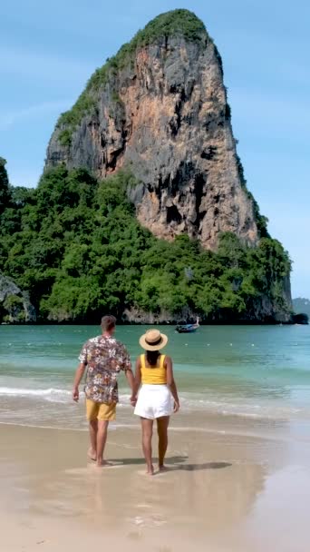 タイのトロピカルホワイトビーチにいる男女のカップル レイレイルビーチ背景に石灰岩の崖があるタイの夏休みにクラビ — ストック動画