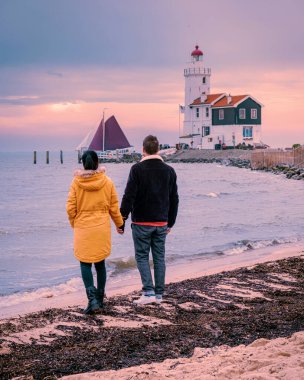 Paard van Marken Lighthouse in the Netherlands, couple visiting the fishing village of Marken Holland during sunset in the winter