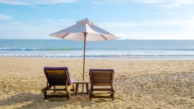 Koh Lanta plajında plaj sandalyeleri, Tayland 'da havuz kenarında şemsiyeli plaj sandalyeleri.