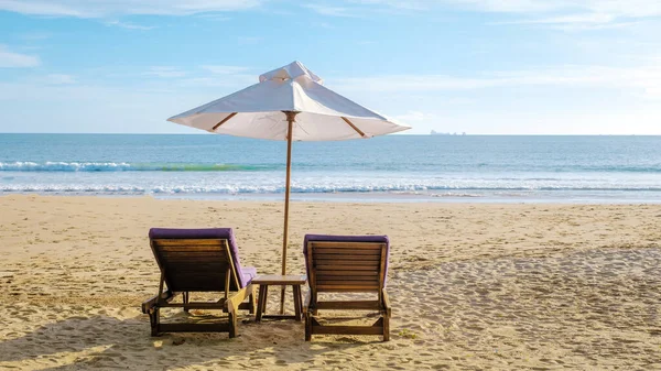 Koh Lanta plajında plaj sandalyeleri, Tayland 'da havuz kenarında şemsiyeli plaj sandalyeleri.