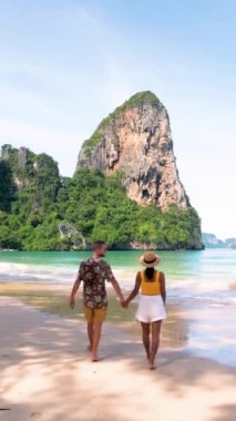 couple of men and women on a tropical white beach in Thailand, Railay Beach Krabi during summer vacation in Thailand with limestone cliffs on the background