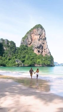 couple of men and women on a tropical white beach in Thailand, Railay Beach Krabi during summer vacation in Thailand with limestone cliffs on the background
