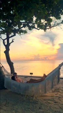 a couple of men and women on a tropical white beach in a hammock during sunset in Thailand, during summer vacation in Thailand Hua Hin