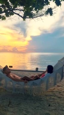 a couple of men and women on a tropical white beach in a hammock during sunset in Thailand, during summer vacation in Thailand Hua Hin