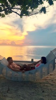 a couple of men and women on a tropical white beach in a hammock during sunset in Thailand, during summer vacation in Thailand Hua Hin