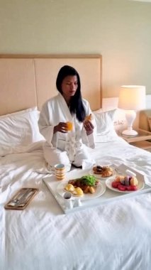 A woman having breakfast in bed, Thai Asian women having breakfast in the bedroom of a luxury hotel 