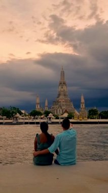 Couple at Wat Arun temple in Bangkok Thailand during sunset.