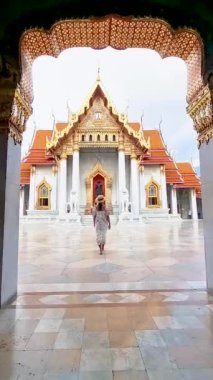 Thai Asian woman visit Wat Benchamabophit temple in Bangkok Thailand, The Marble temple in Bangkok. Tourist with a hat by a temple in Bangkok