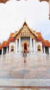 Thai Asian woman visit Wat Benchamabophit temple in Bangkok Thailand, The Marble temple in Bangkok. Tourist with a hat by a temple in Bangkok