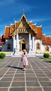 Thai Asian woman visit Wat Benchamabophit temple in Bangkok Thailand, The Marble temple in Bangkok. Tourist with a hat by a temple in Bangkok
