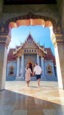 A couple of men and women visit Wat Benchamabophit temple in Bangkok Thailand, tourists visit The Marble temple in Bangkok. 