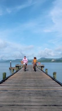 a couple of men and women bicycle on a wooden pier of a tropical Island during vacation.
