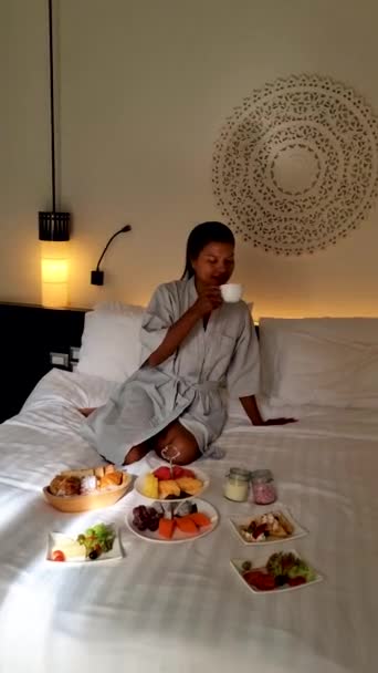 ベッドで朝食をとる女性高級ホテルの寝室で朝食をとるタイ人アジア人女性 — ストック動画