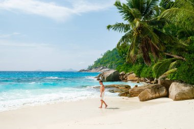 Young men in a swim short on a white tropical beach with palm trees Petite Anse beach Mahe Tropical Seychelles Islands. 