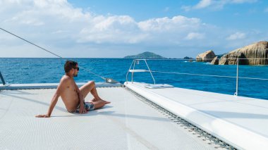 Young men on a trip with a Sailing boat at the Tropical Seychelles Islands.