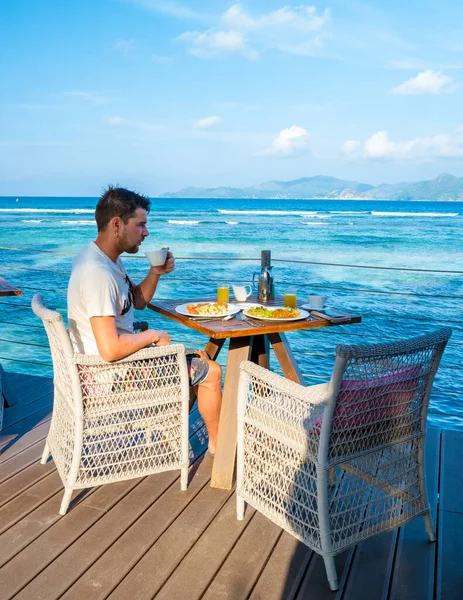 Men Drinking Coffe Breakfast Table View Turquoise Colored Ocean Digue — Zdjęcie stockowe