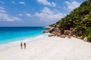 Couple men and woman walking at a tropical beach, Drone view from above Seychelles Cocos Island.