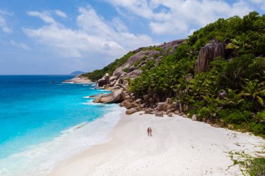 men and woman walking at a tropical beach, Drone view from above Seychelles Cocos Island.