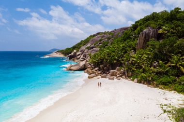 men and woman walking at a tropical beach, Drone view from above Seychelles Cocos Island.