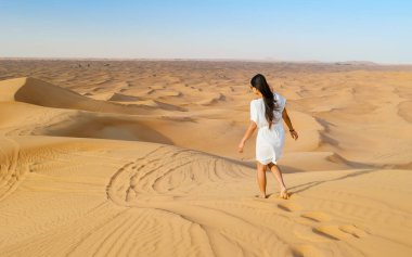 Young Asian woman walking in the desert, Sand dunes of Dubai United Arab Emirates