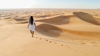 Young Asian woman walking in the desert, Sand dunes of Dubai United Arab Emirates