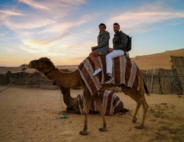 Couple riding a camel during Dubai desert safari at the safari camp, Dubai United Arab Emirates