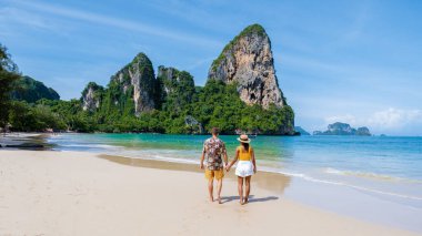 Railay Beach Krabi Tayland, Railay Krabi 'nin tropikal plajı, kumsalda bir çift kadın ve erkek, Tayland' da geleneksel uzun bir teknesi olan huzurlu Railay Kumsalı manzarası..