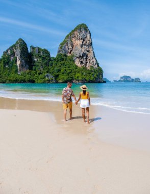 Railay Beach Krabi Tayland, Railay Krabi 'nin tropikal plajı, kumsalda bir çift kadın ve erkek, Tayland' da geleneksel uzun bir teknesi olan huzurlu Railay Kumsalı manzarası..