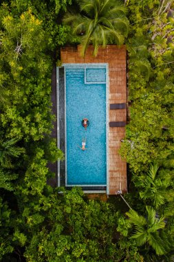 drone view of a swimming pool in the jungle, aerial view of a drone above a swimming pool in the rainforest, men and women in a pool
