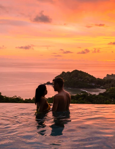 熱帯の島で休暇中にスイミングプールでロマンチックな男女のカップル 日没時にインフィニティプールの男と女 豪華なプールヴィラでの贅沢な休暇 — ストック写真