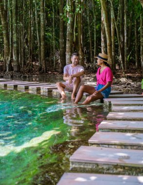 couple of men and women visit the Emerald pool and Blue pool in Krabi Thailand, tropical lagoon in a national park with trees, and mangroves with crystal clear water