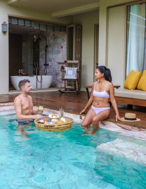 couple of men and woman having breakfast in a pool on a luxury vacation at a pool villa in the rainforest jungle mountains