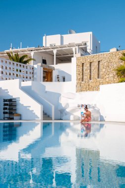 Young men read a book by the swimming pool during vacation. a young man in a swim shorts by the pool during vacation