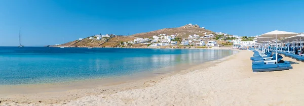 Mykonos beach during summer with umbrella and luxury beach chairs beds, blue ocean with the mountain at Elia beach Mikonos Greece.