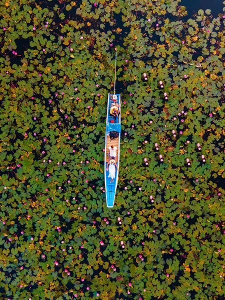 赤い蓮の海での日の出 ハーン湖 うどんタイ タイの赤い蓮の湖で日の出の間に木製のボートの男性と女性のカップル — ストック写真