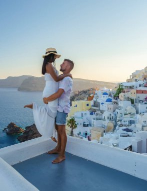Couple hugging and kissing on a romantic vacation in Santorini Greece, men and women visit the whitewashed Greek village of Oia . 