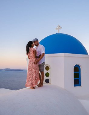 Couple hugging and kissing on a romantic vacation in Santorini Greece, men and women visit the whitewashed Greek village of Oia . 
