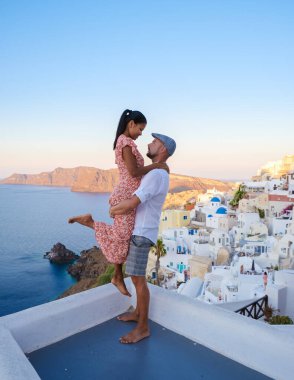 Couple watching the sunset on vacation in Santorini Greece, men and women visit the Greek village of Oia Santorini. 